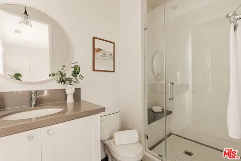 a bathroom with a granite countertop sink a toilet and shower
