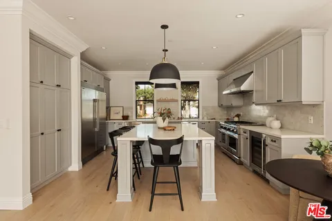 a kitchen with stainless steel appliances granite countertop a stove a sink dishwasher a dining table and chairs with wooden floor