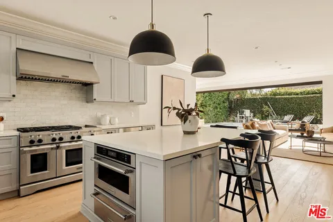 a kitchen with stainless steel appliances a stove a table and chairs with wooden floor