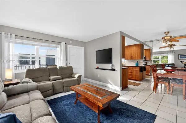a living room with furniture a flat screen tv and kitchen view