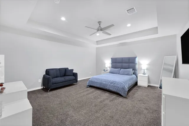 a bedroom with a bed a couch and a potted plant on a dresser