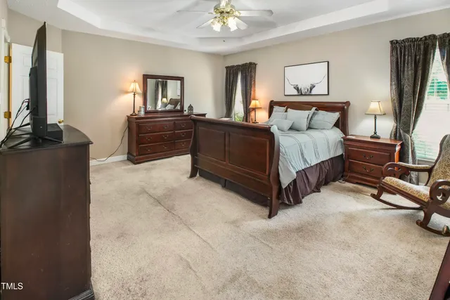 a spacious bedroom with a bed window and dresser