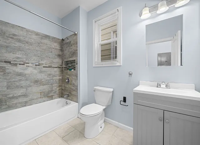 a bathroom with a toilet a sink a mirror a bathtub and shower