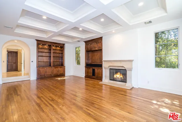 an empty room with wooden floor fireplace and windows