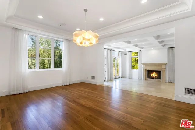 an empty room with wooden floor a chandelier a fireplace and window