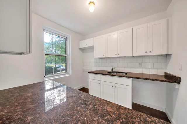 a kitchen with granite countertop a sink stove and cabinets