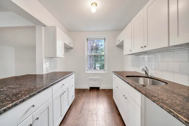 a kitchen with granite countertop white cabinets and wooden floor