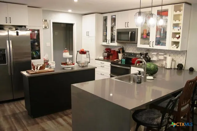 a kitchen with stainless steel appliances a sink a microwave a refrigerator and chairs