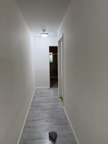 a view of a hallway with wooden floor and a carpet