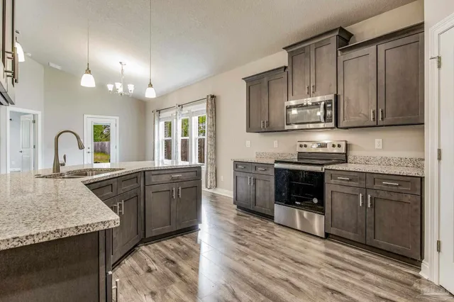 a kitchen with granite countertop a refrigerator stove and microwave