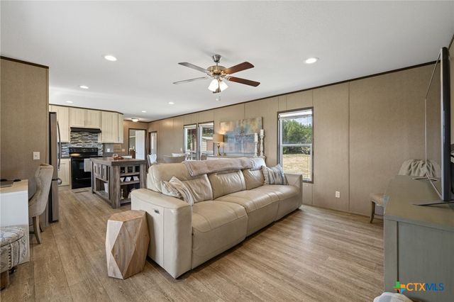 a kitchen with stainless steel appliances kitchen island granite countertop a dining table chairs and a refrigerator