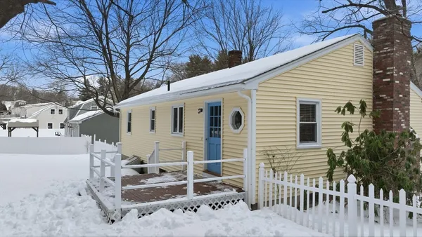 a view of a house with a small yard and large tree