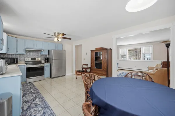 a kitchen with stainless steel appliances kitchen island granite countertop a refrigerator a stove a sink dishwasher a dining table and chairs with wooden floor