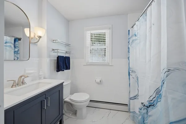 a bathroom with a sink a toilet a mirror and shower