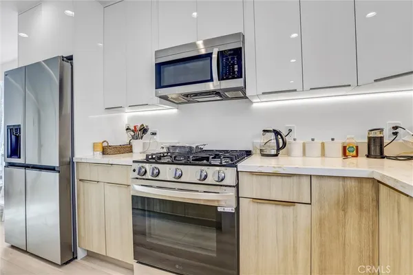 a kitchen with stainless steel appliances granite countertop white cabinets a refrigerator and a stove top oven