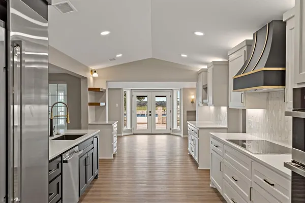 a large kitchen with stainless steel appliances a large counter top a sink a refrigerator and cabinets