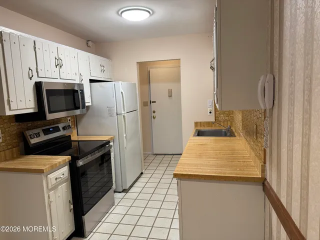 a kitchen with a sink a stove top oven a refrigerator and a window