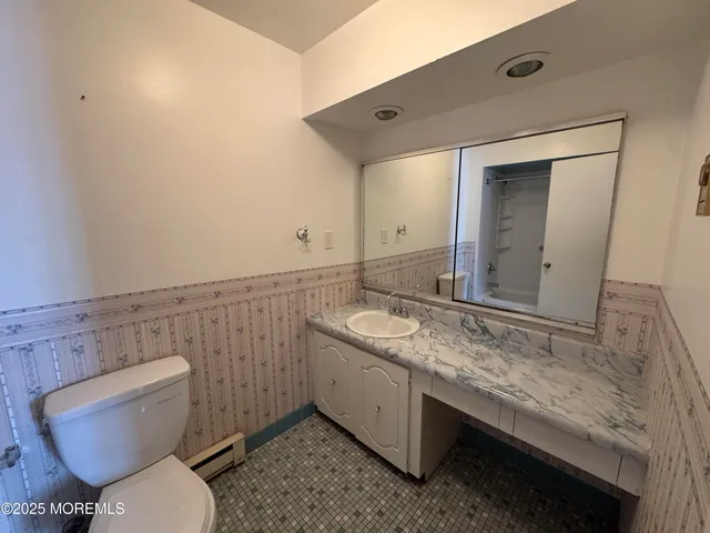 a bathroom with a granite countertop toilet sink and mirror