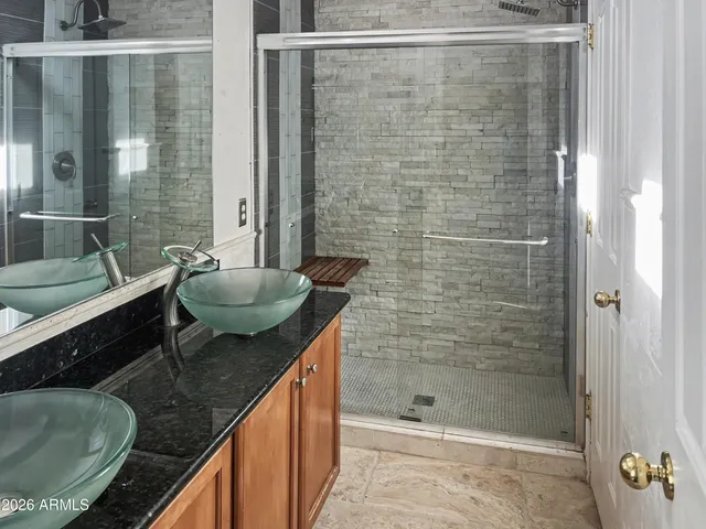 a bathroom with a granite countertop sink a mirror and shower