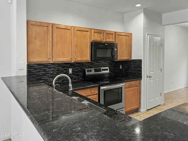 a kitchen with granite countertop a sink a stove and microwave