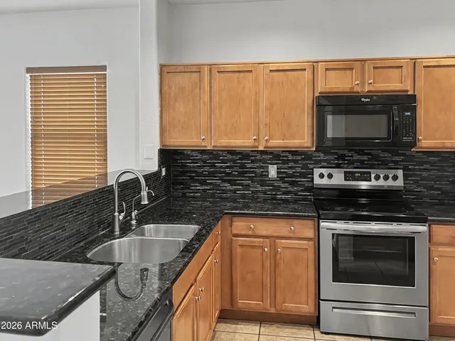 a kitchen with granite countertop a sink stove and microwave