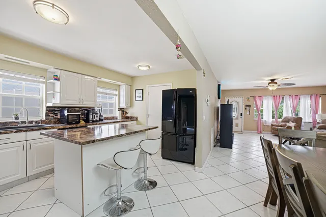 a kitchen with stainless steel appliances granite countertop a stove a refrigerator a sink a dining table and chairs with white cabinets