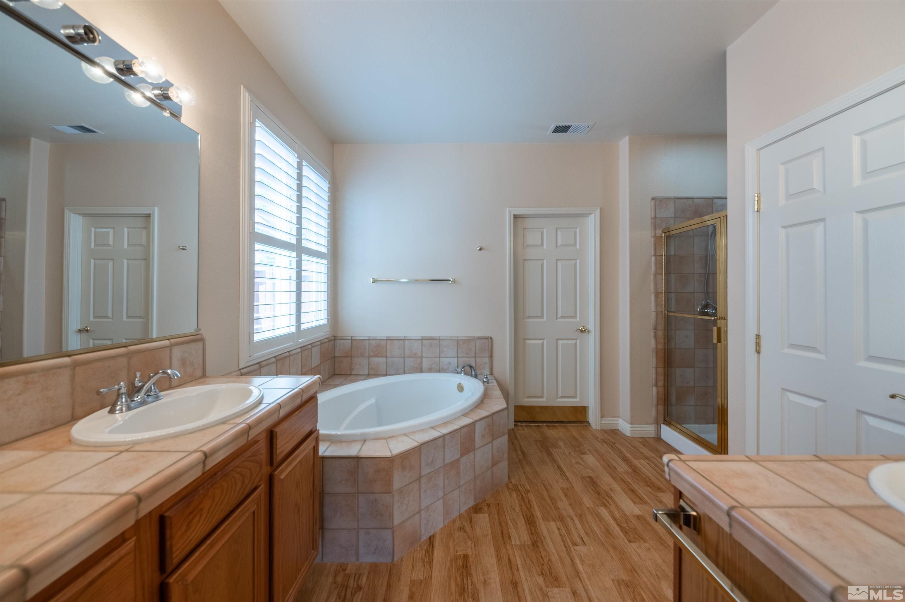 1416 Wild Wolf Way Reno, NV 89521 - Photo 23 of 39 a spacious bathroom with a granite countertop sink a mirror and a bathtub