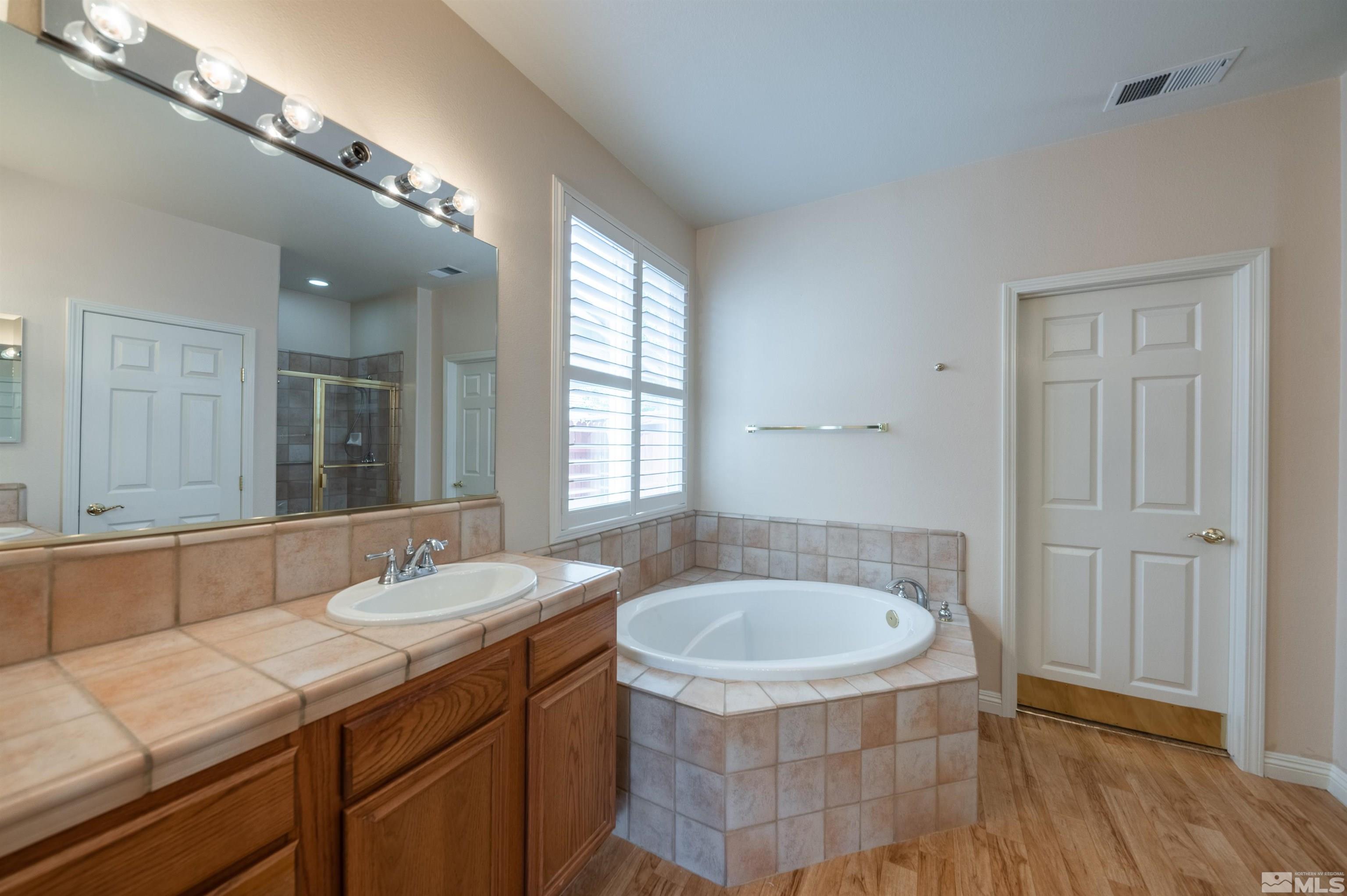 1416 Wild Wolf Way Reno, NV 89521 - Photo 24 of 39 a bathroom with a sink a mirror and a bathtub