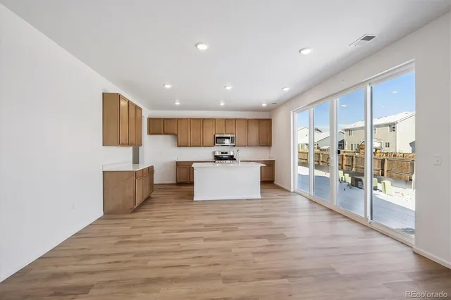 a room with kitchen island stainless steel appliances a couch and a large window