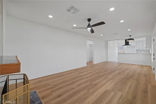 a view of empty room with wooden floor and ceiling fan