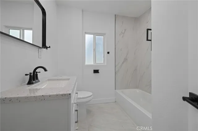 a bathroom with a granite countertop sink a toilet and bathtub