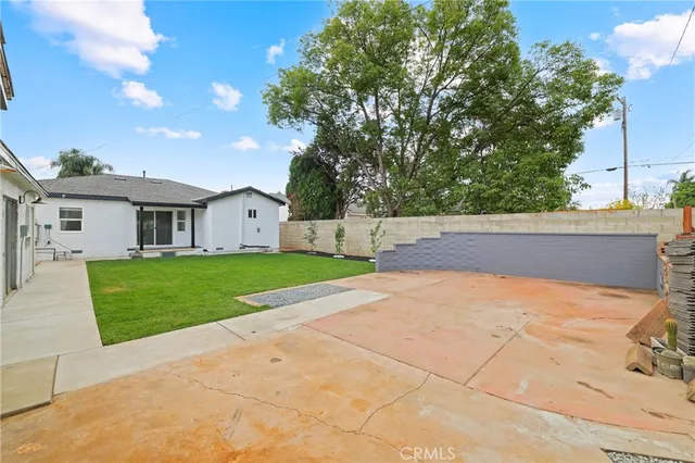 a view of white house with a big yard and large tree