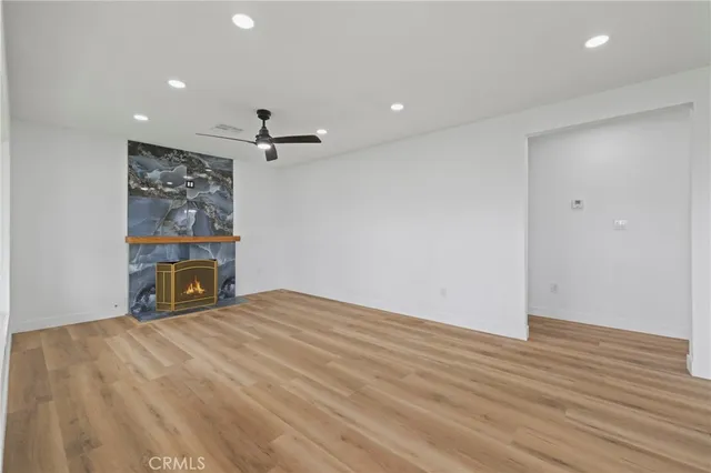 a view of an empty room with wooden floor and a ceiling fan