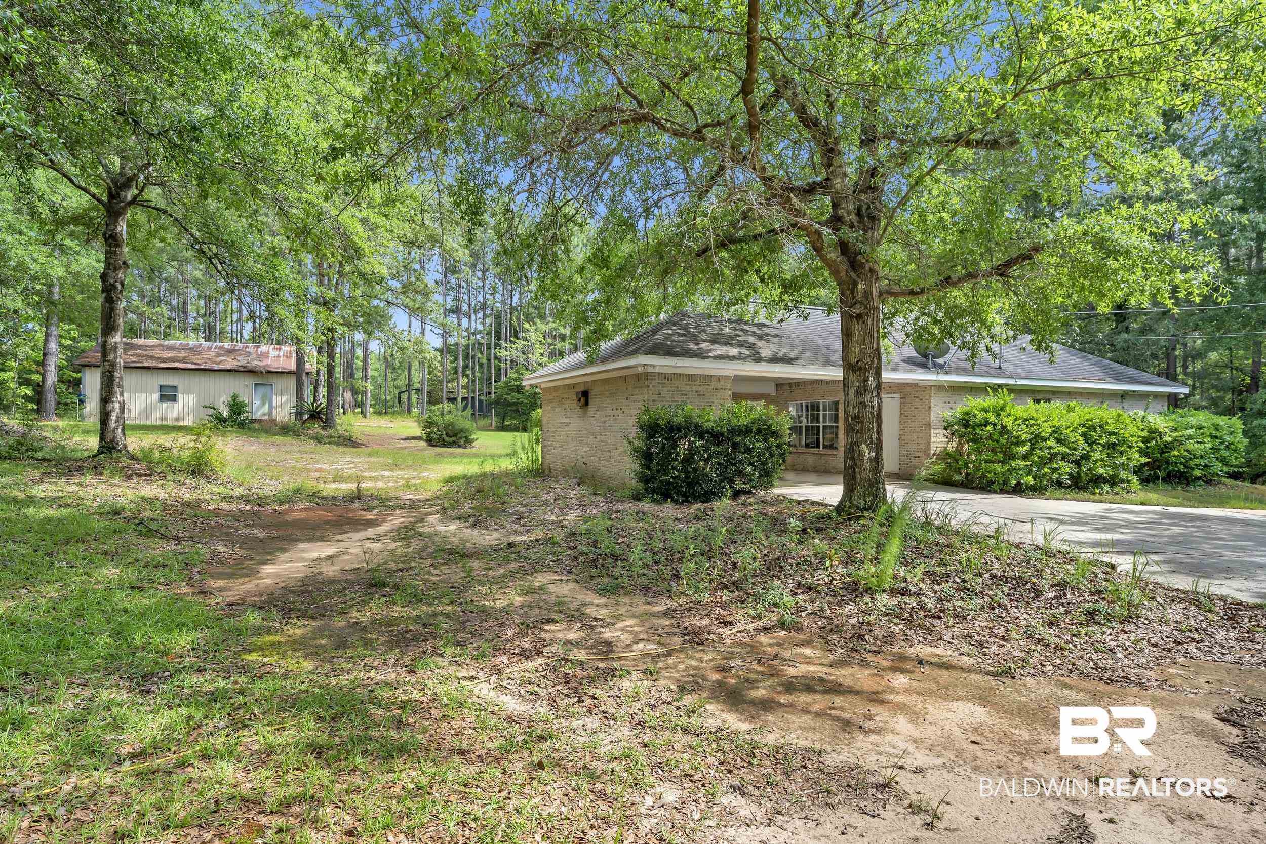 14960 Howells Ferry Road Wilmer, AL 36587 - Photo 4 of 22 Brick exterior residence with an attached garage, surrounded by mature trees and lush green landscaping