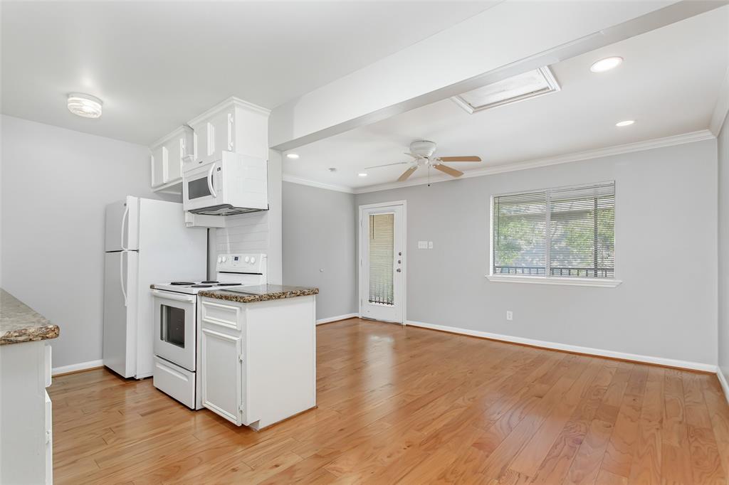 4931 Junius Street, Unit 8 Dallas, TX 75214 - Photo 13 of 31 a kitchen with stainless steel appliances a stove a sink and white cabinets with wooden floor