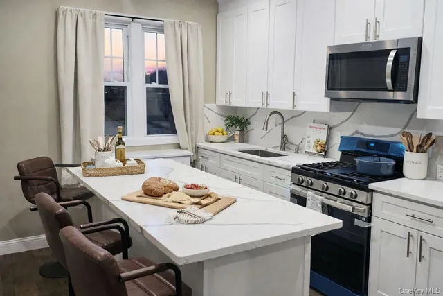 a kitchen with a stove a sink and white cabinets