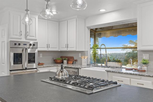 a large white kitchen with a stove and wooden floor