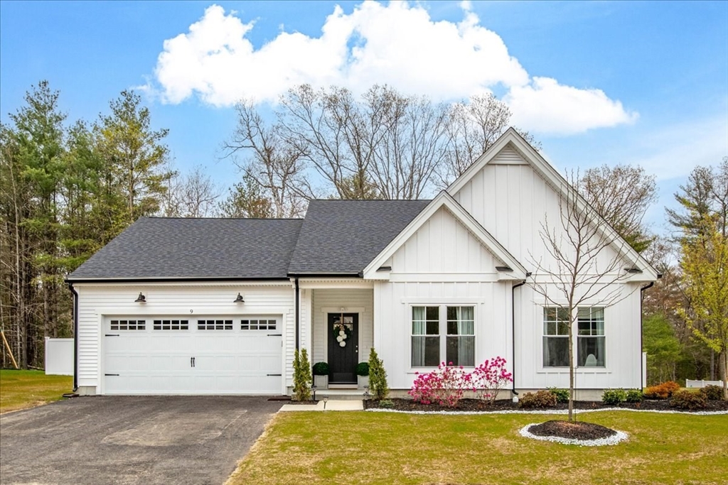 a view of a white house with large windows and a table and chairs under an umbrella