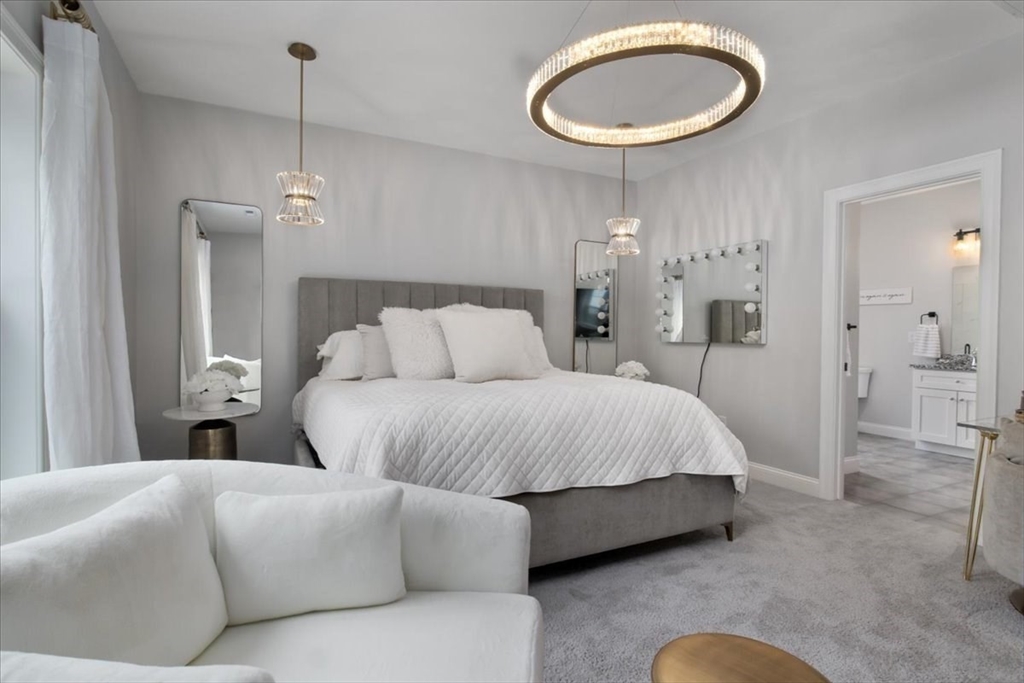 9 Iris Lane Bellingham, MA 02019 - Photo 17 of 34 a spacious bedroom with a bed a chandelier and a mirror