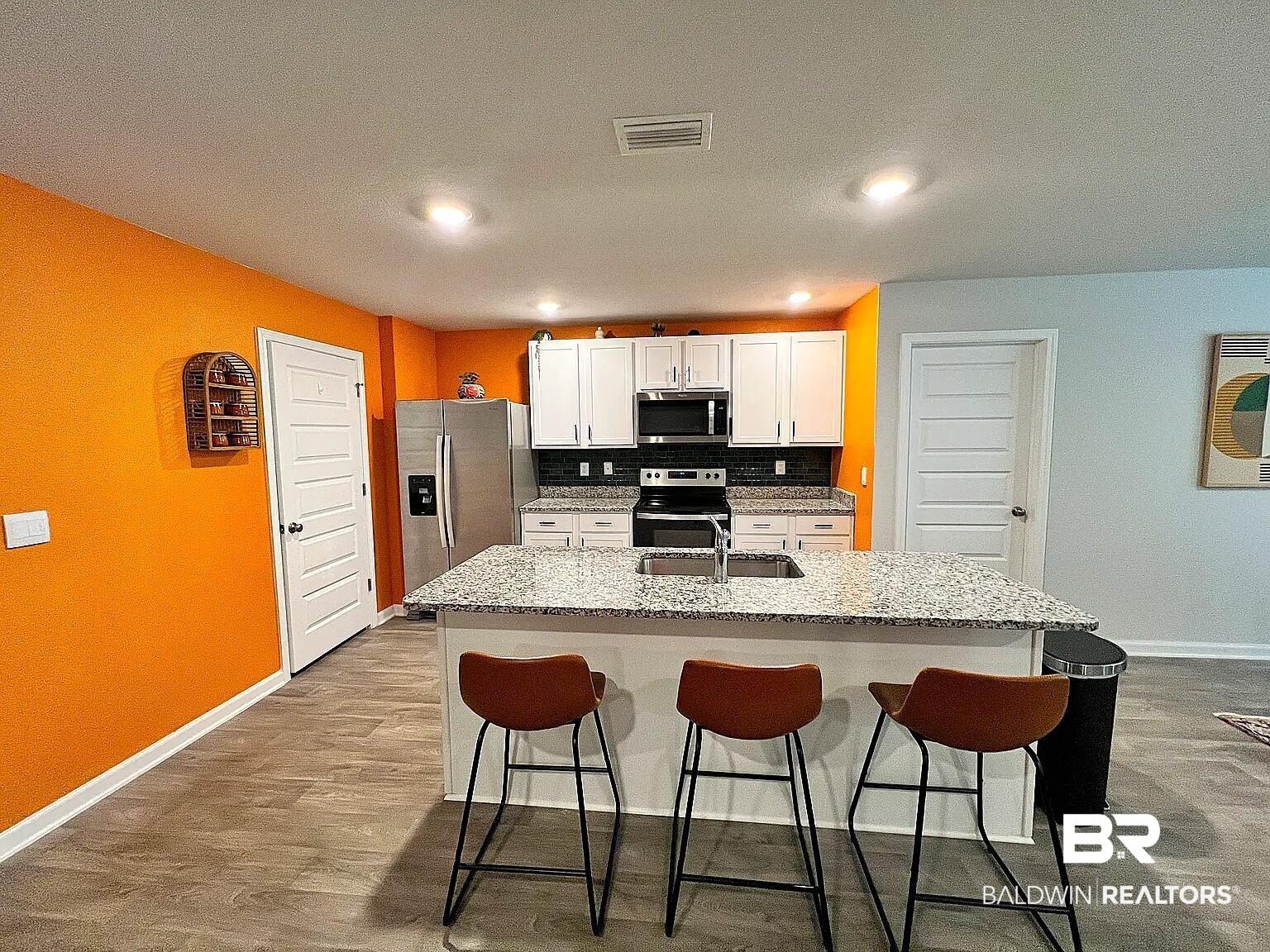23915 Veranda Circle Elberta, AL 36530 - Photo 10 of 16 Kitchen with tasteful backsplash, a breakfast bar, white cabinets, appliances with stainless steel finishes, and an island with sink