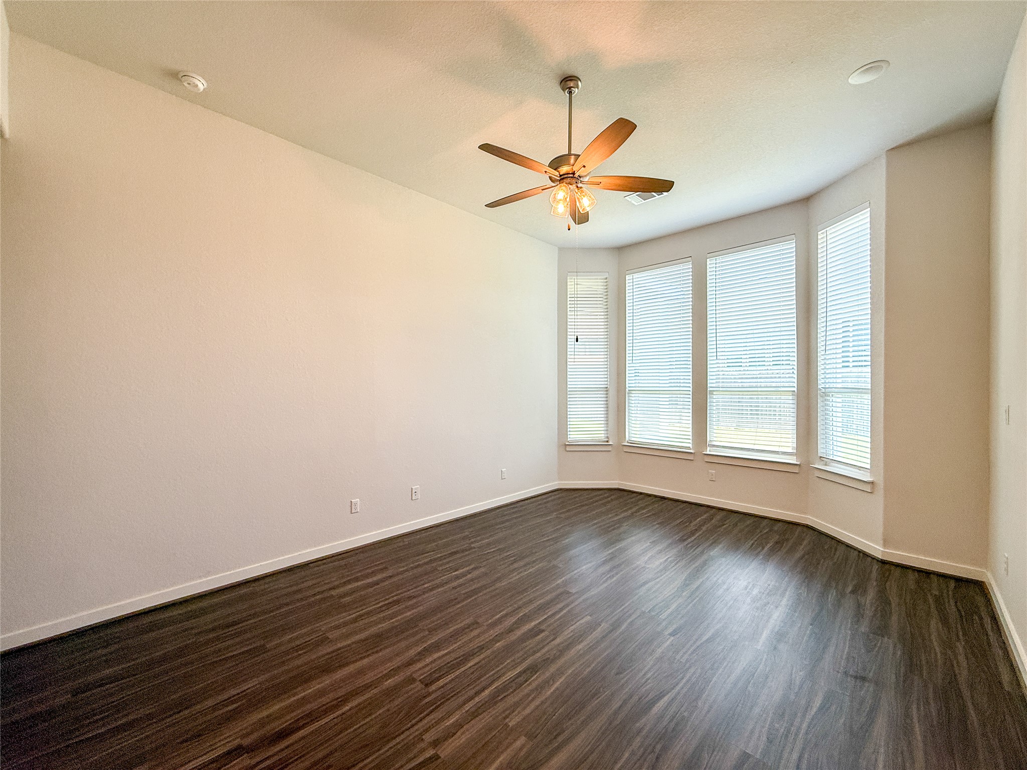 249 Heartleaf Road San Marcos, TX 78666 - Photo 19 of 38 A quiet bedroom retreat with bay windows and dark hardwood-style flooring.