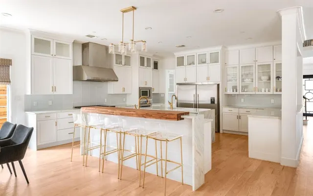a kitchen with stainless steel appliances kitchen island a table chairs in it and wooden floors