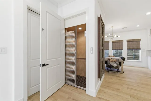 a view of a hallway with wooden floor and a bathroom