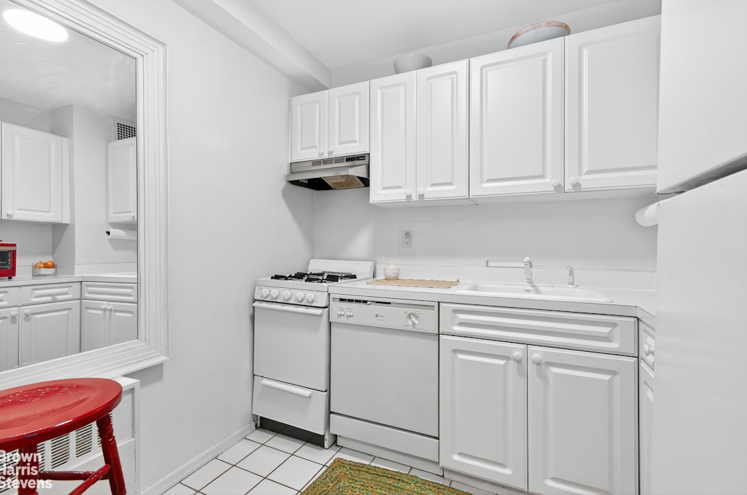 520 East 72nd Street, Unit 3R Manhattan, NY 10021 - Photo 6 of 16 a kitchen with white cabinets and white appliances