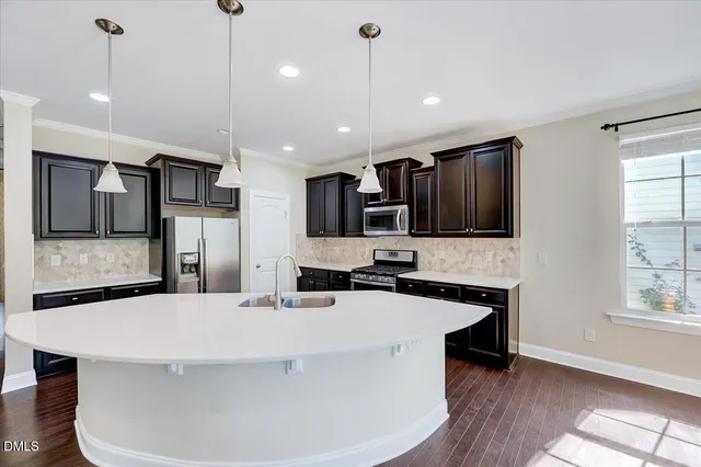 a kitchen with stainless steel appliances a sink a stove a refrigerator a center island a stove and a window