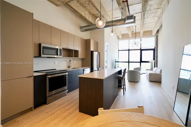 a kitchen with stainless steel appliances kitchen island granite countertop a stove a refrigerator a sink a dining table and chairs with wooden floor