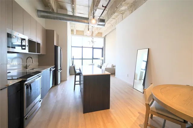 a living room with stainless steel appliances granite countertop furniture wooden floor and a window