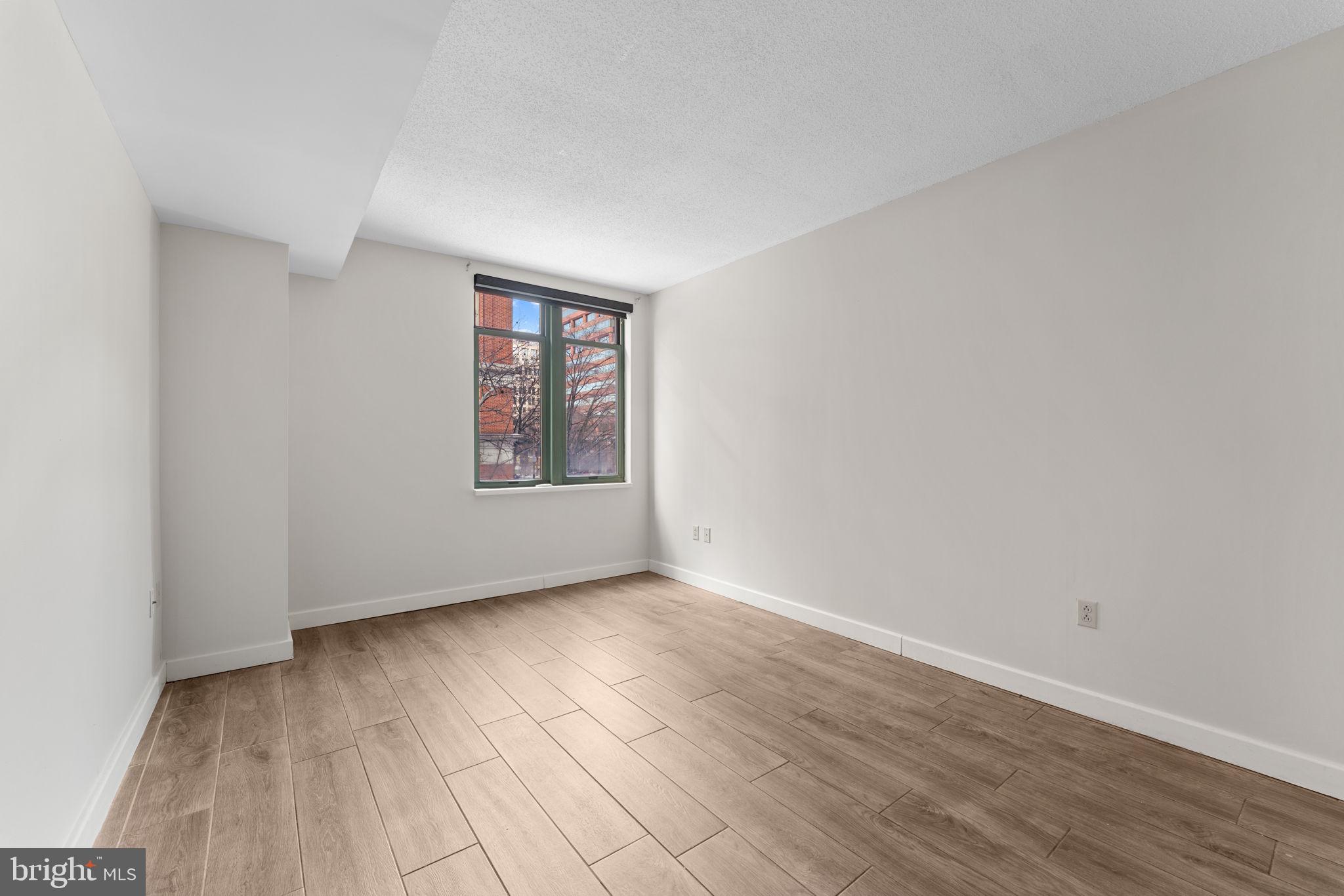 1150 K Street Northwest, Unit 306 Washington, DC 20005 - Photo 14 of 23 an empty room with wooden floor and windows