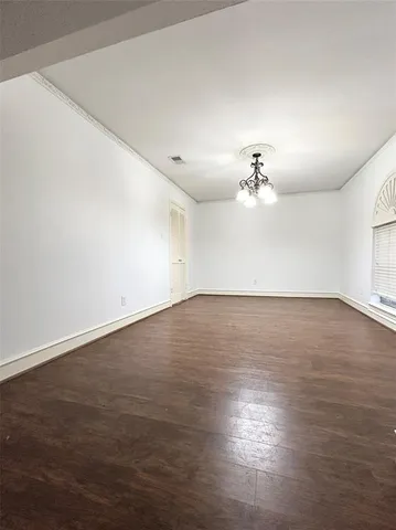an empty room with wooden floor chandelier fan and windows