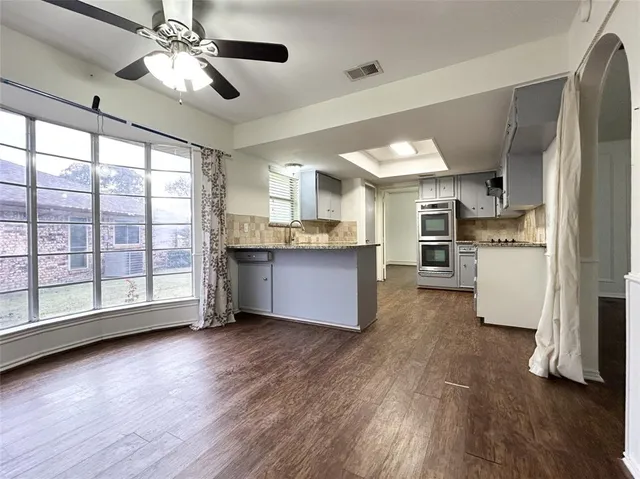 a open kitchen with stainless steel appliances granite countertop a stove oven and a refrigerator with wooden floors